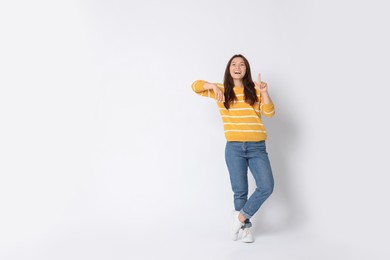 Photo of Smiling woman pointing at something on white background. Space for text