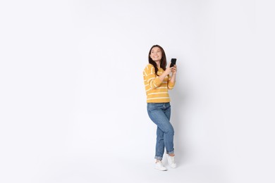 Photo of Smiling woman using smartphone on white background. Space for text