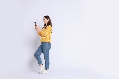 Photo of Smiling woman using smartphone on white background. Space for text