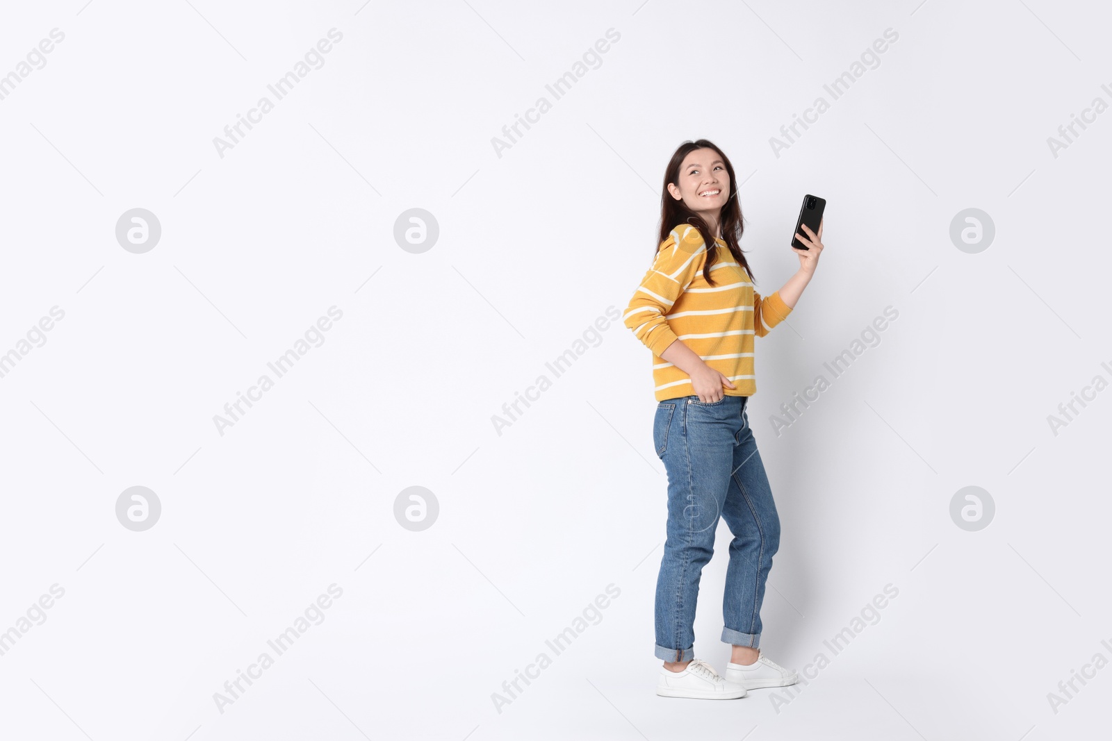 Photo of Smiling woman using smartphone on white background. Space for text