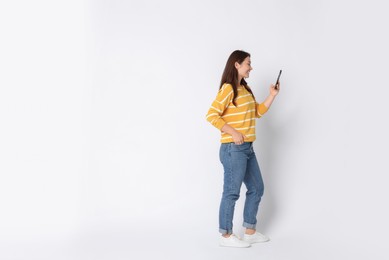 Photo of Smiling woman using smartphone on white background. Space for text