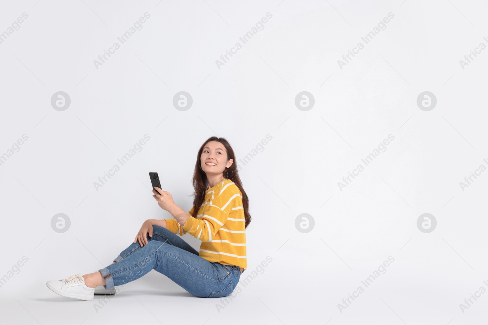 Photo of Smiling woman using smartphone on white background. Space for text