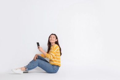 Smiling woman using smartphone on white background. Space for text