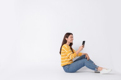 Photo of Smiling woman using smartphone on white background. Space for text