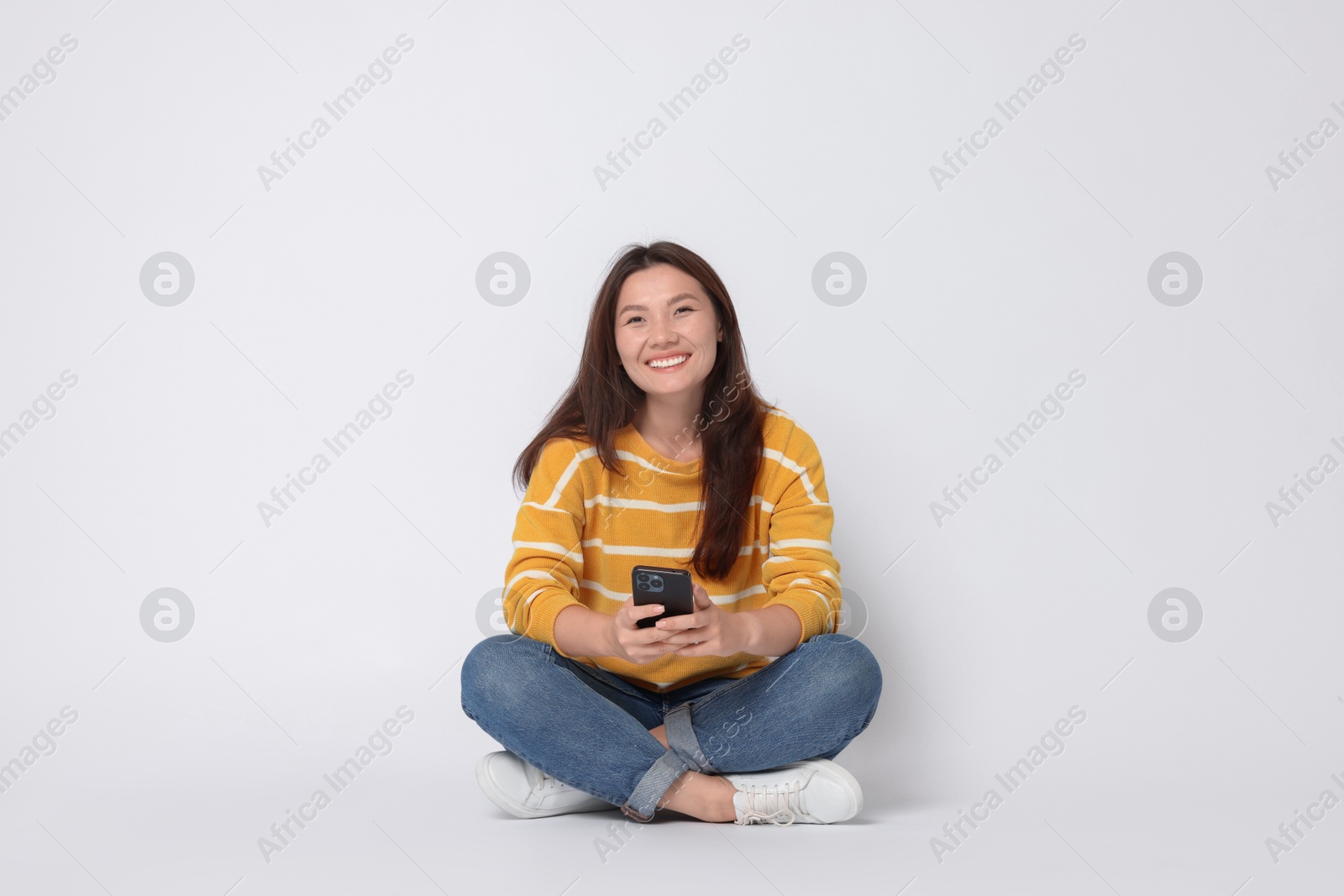 Photo of Smiling woman with smartphone on white background