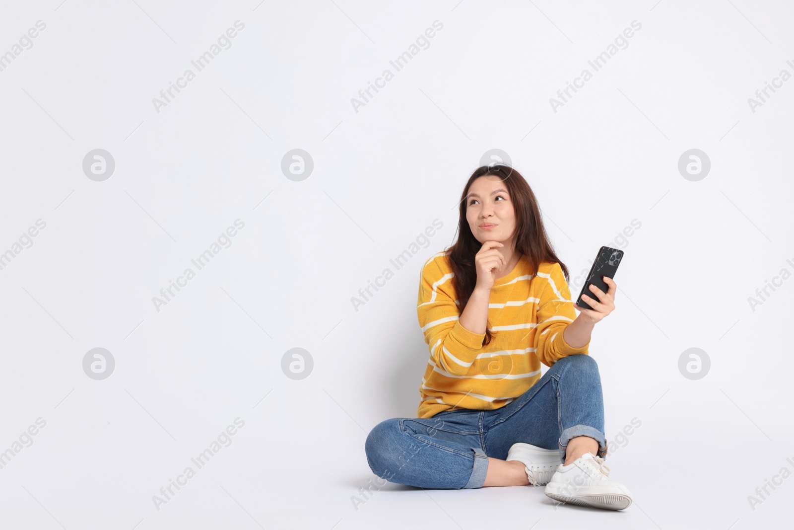 Photo of Young woman with smartphone on white background. Space for text