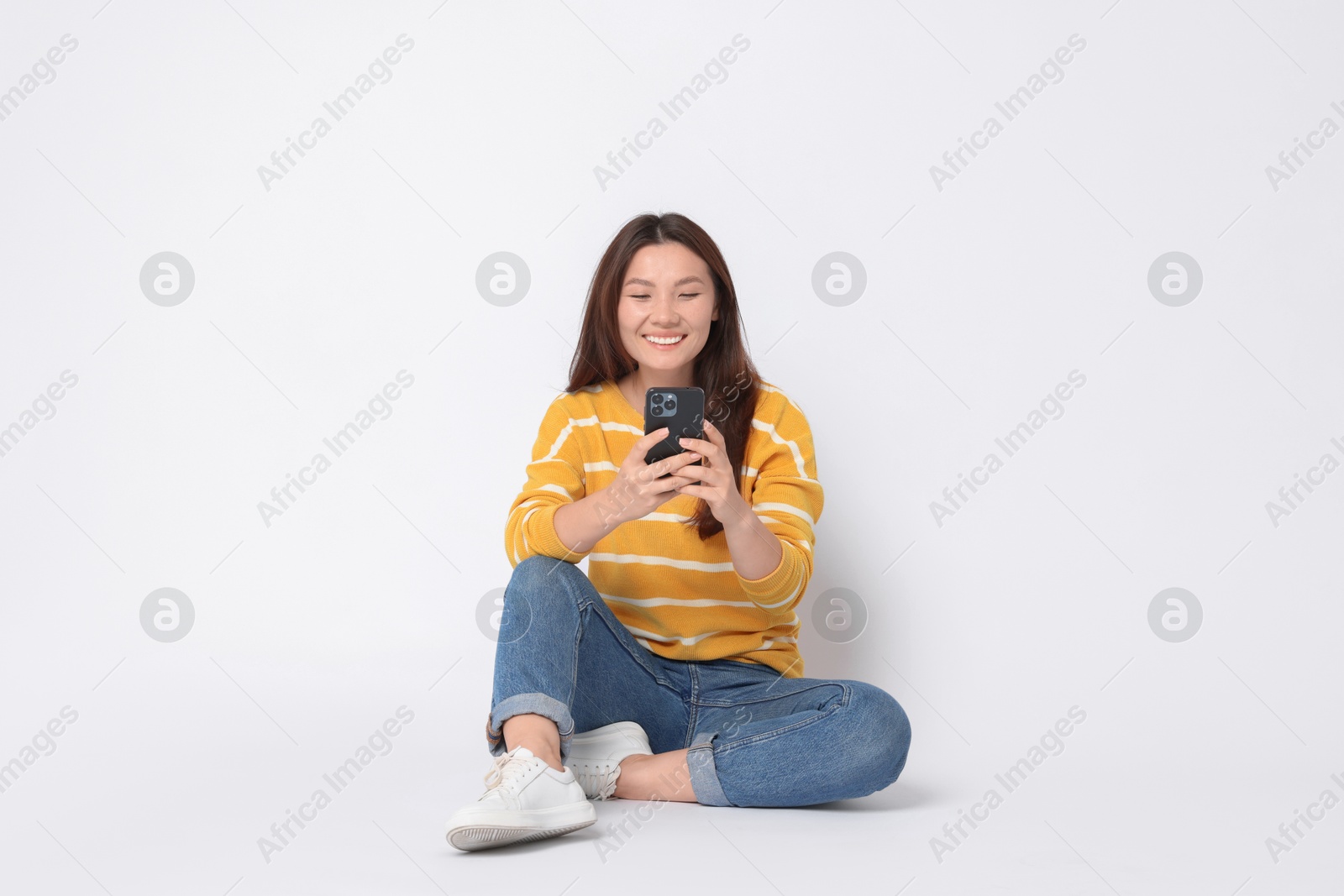 Photo of Smiling woman using smartphone on white background