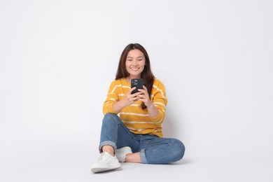 Smiling woman using smartphone on white background