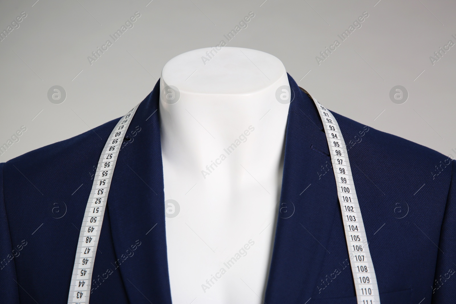 Photo of Male mannequin with elegant suit jacket and measuring tape on grey background, closeup