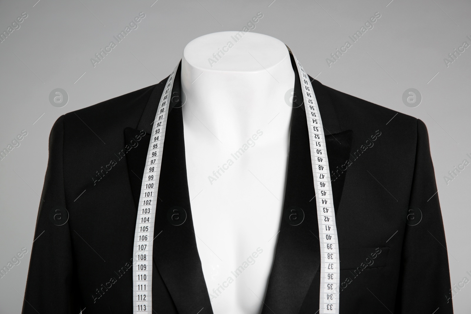 Photo of Male mannequin with elegant suit jacket and measuring tape on grey background, closeup