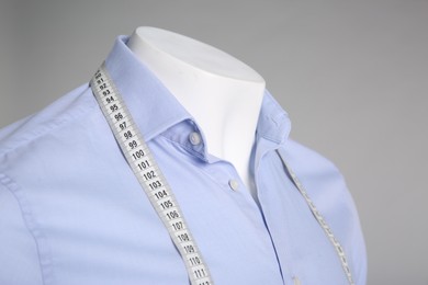 Photo of Male mannequin with elegant shirt and measuring tape on grey background, closeup