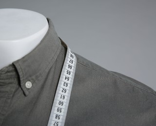 Photo of Male mannequin with elegant shirt and measuring tape on grey background, closeup