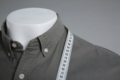 Male mannequin with elegant shirt and measuring tape on grey background, closeup