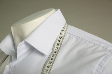 Male mannequin with elegant shirt and measuring tape on grey background, closeup