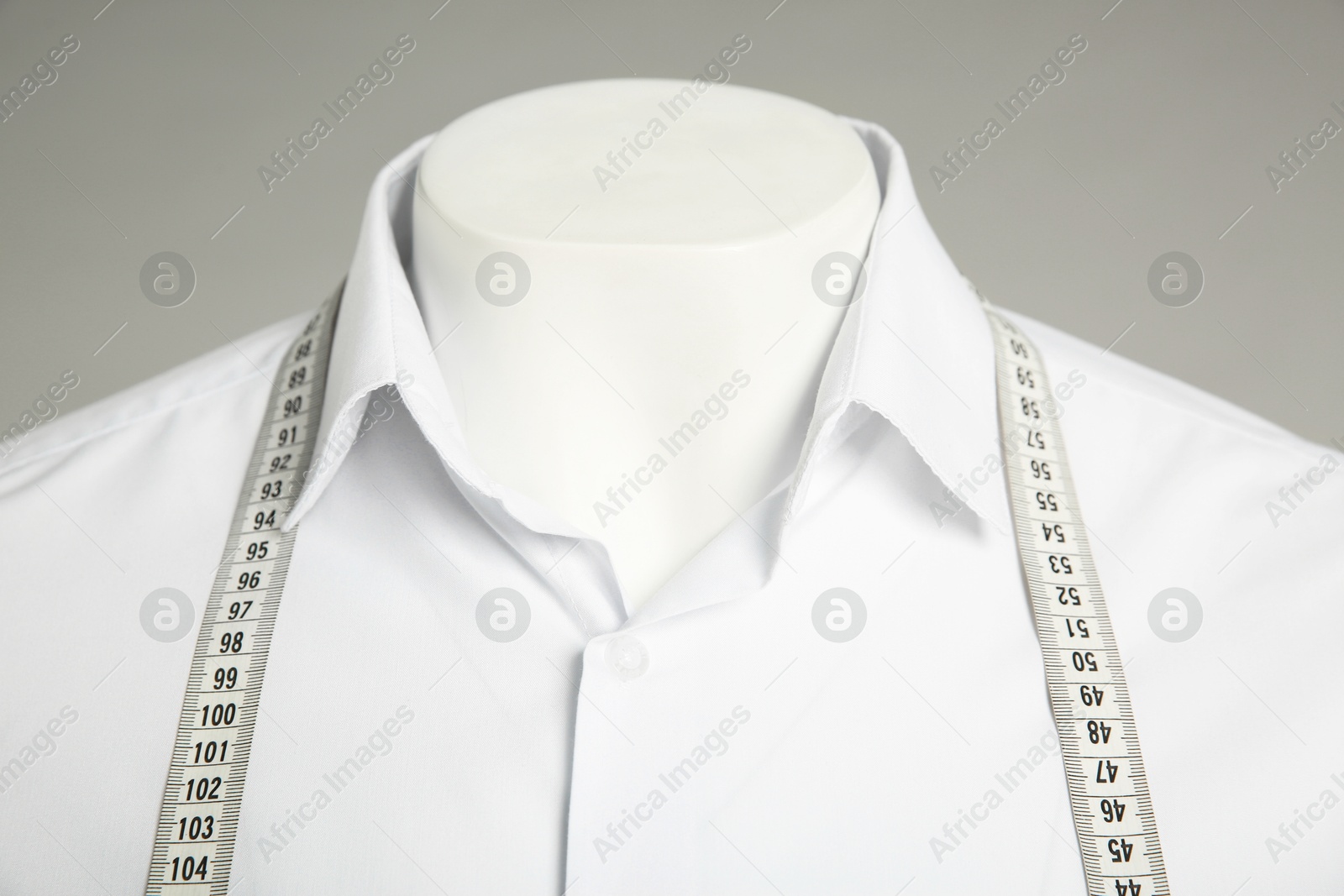 Photo of Male mannequin with elegant shirt and measuring tape on grey background, closeup