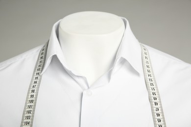 Male mannequin with elegant shirt and measuring tape on grey background, closeup