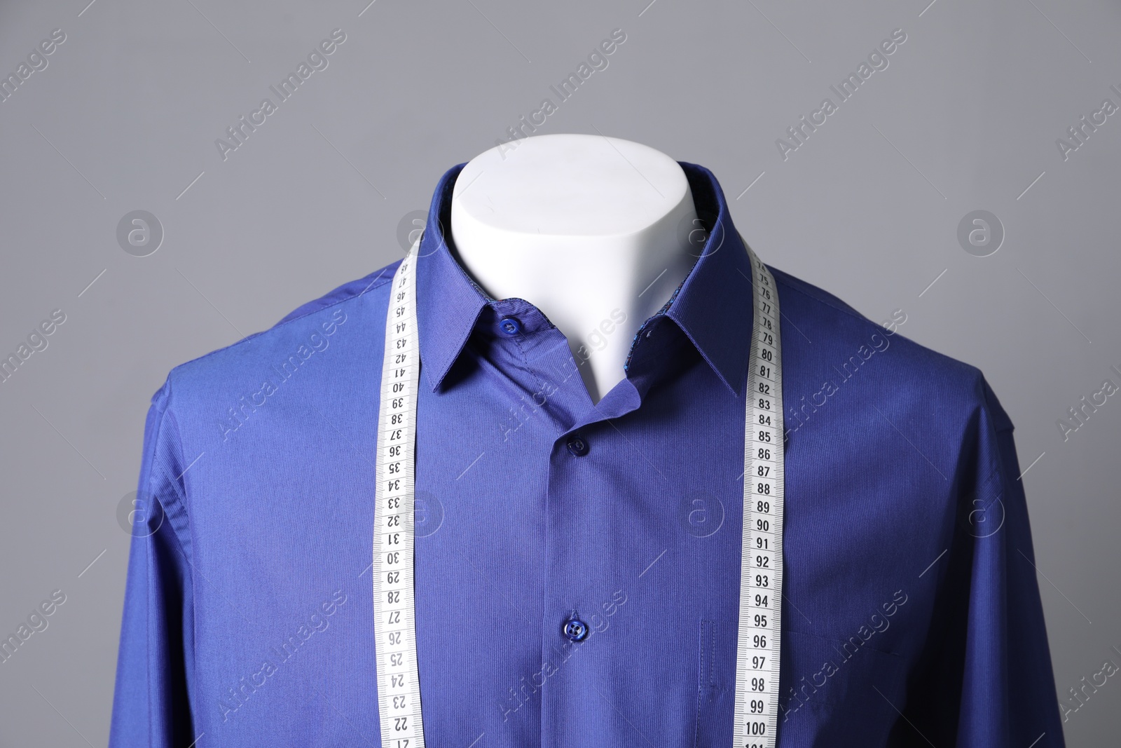 Photo of Male mannequin with blue shirt and measuring tape on grey background