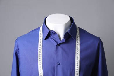 Male mannequin with blue shirt and measuring tape on grey background