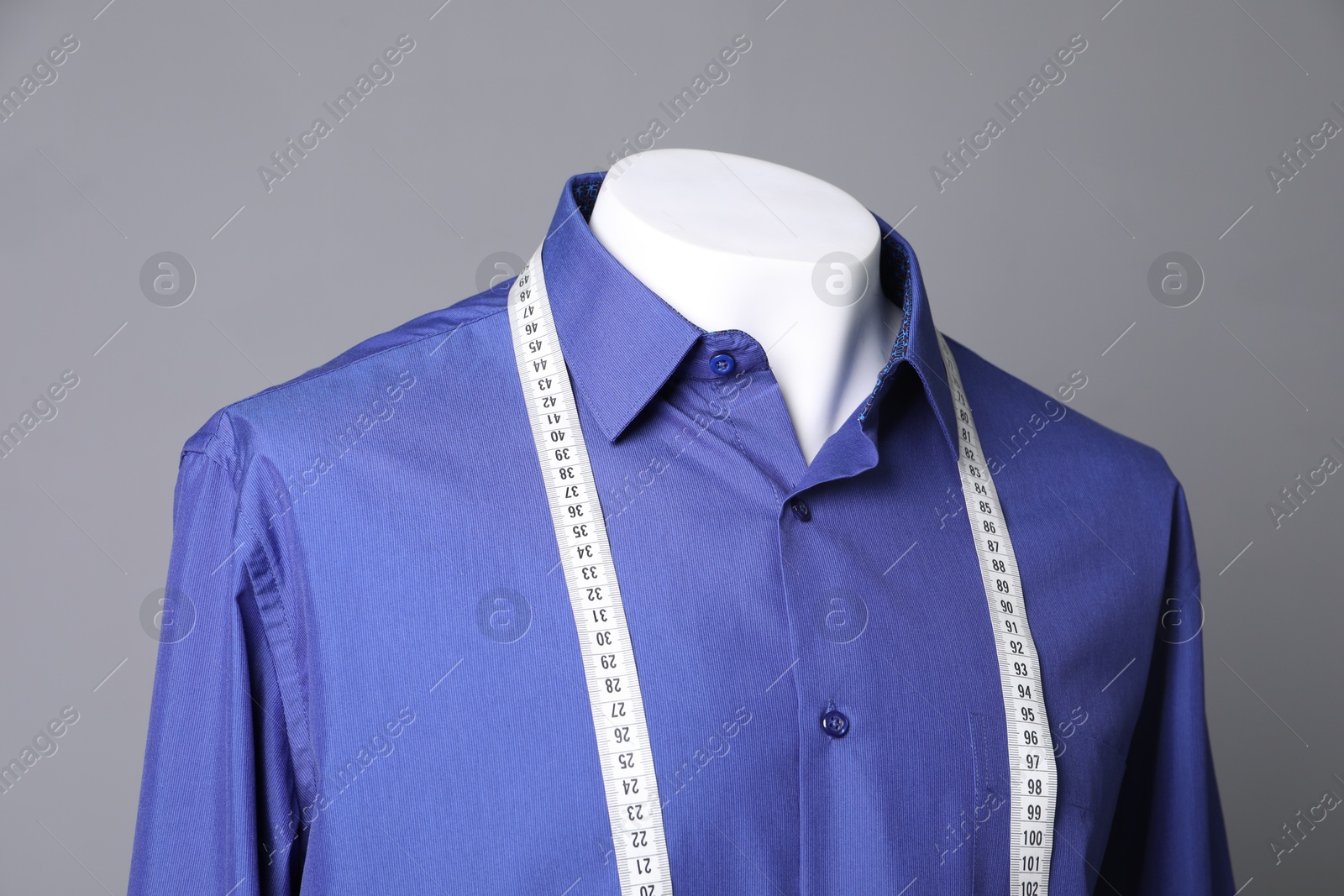 Photo of Male mannequin with blue shirt and measuring tape on grey background