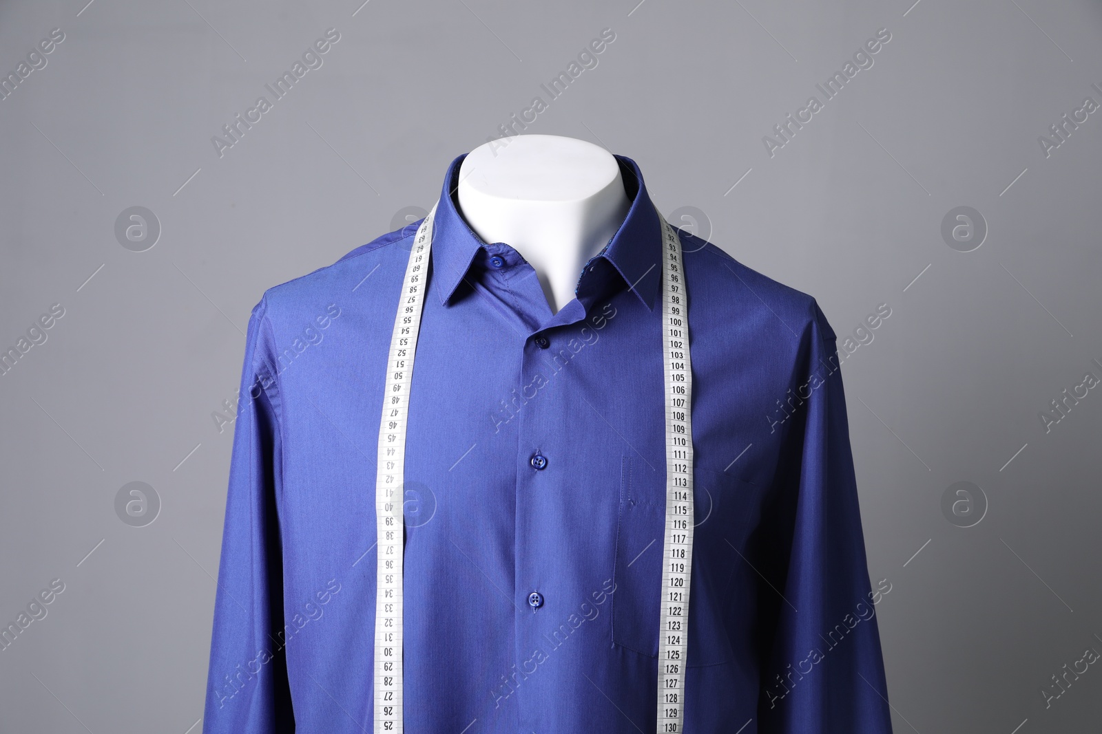 Photo of Male mannequin with blue shirt and measuring tape on grey background