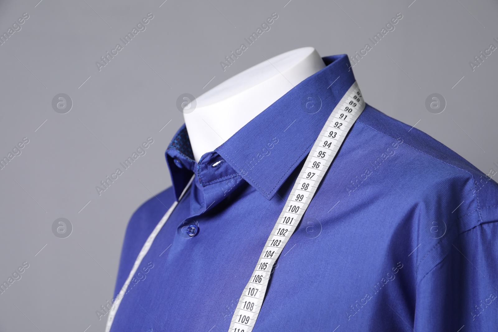 Photo of Male mannequin with blue shirt and measuring tape on grey background, closeup