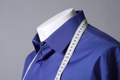 Photo of Male mannequin with blue shirt and measuring tape on grey background, closeup