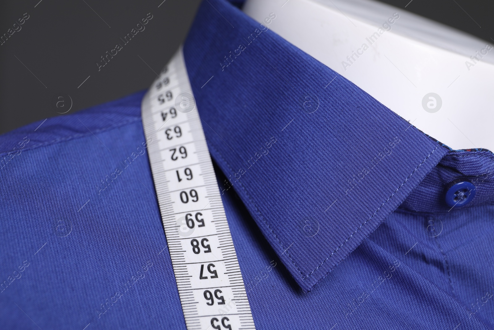 Photo of Mannequin with blue shirt and measuring tape on grey background, closeup