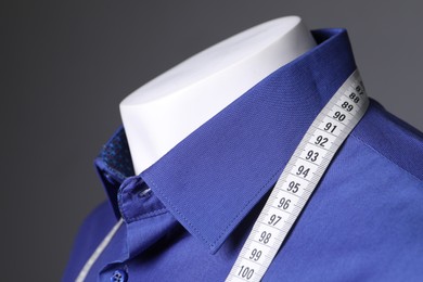 Photo of Male mannequin with blue shirt and measuring tape on grey background, closeup