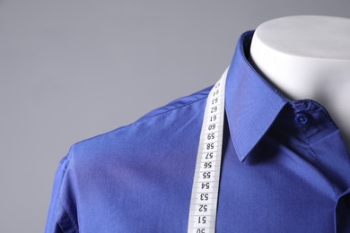 Photo of Male mannequin with blue shirt and measuring tape on grey background, closeup