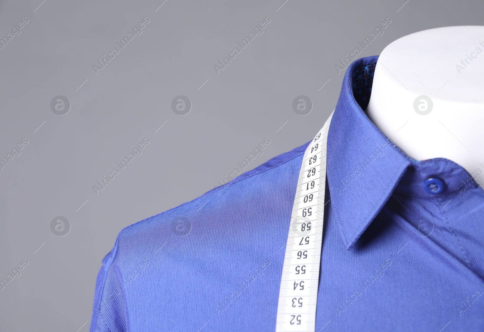 Photo of Male mannequin with blue shirt and measuring tape on grey background, closeup