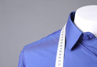 Photo of Male mannequin with blue shirt and measuring tape on grey background, closeup