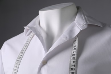 Photo of Male mannequin with white shirt and measuring tape on grey background, closeup