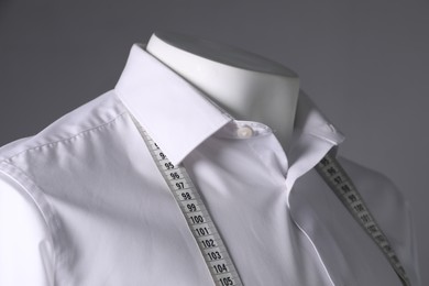 Male mannequin with white shirt and measuring tape on grey background, closeup