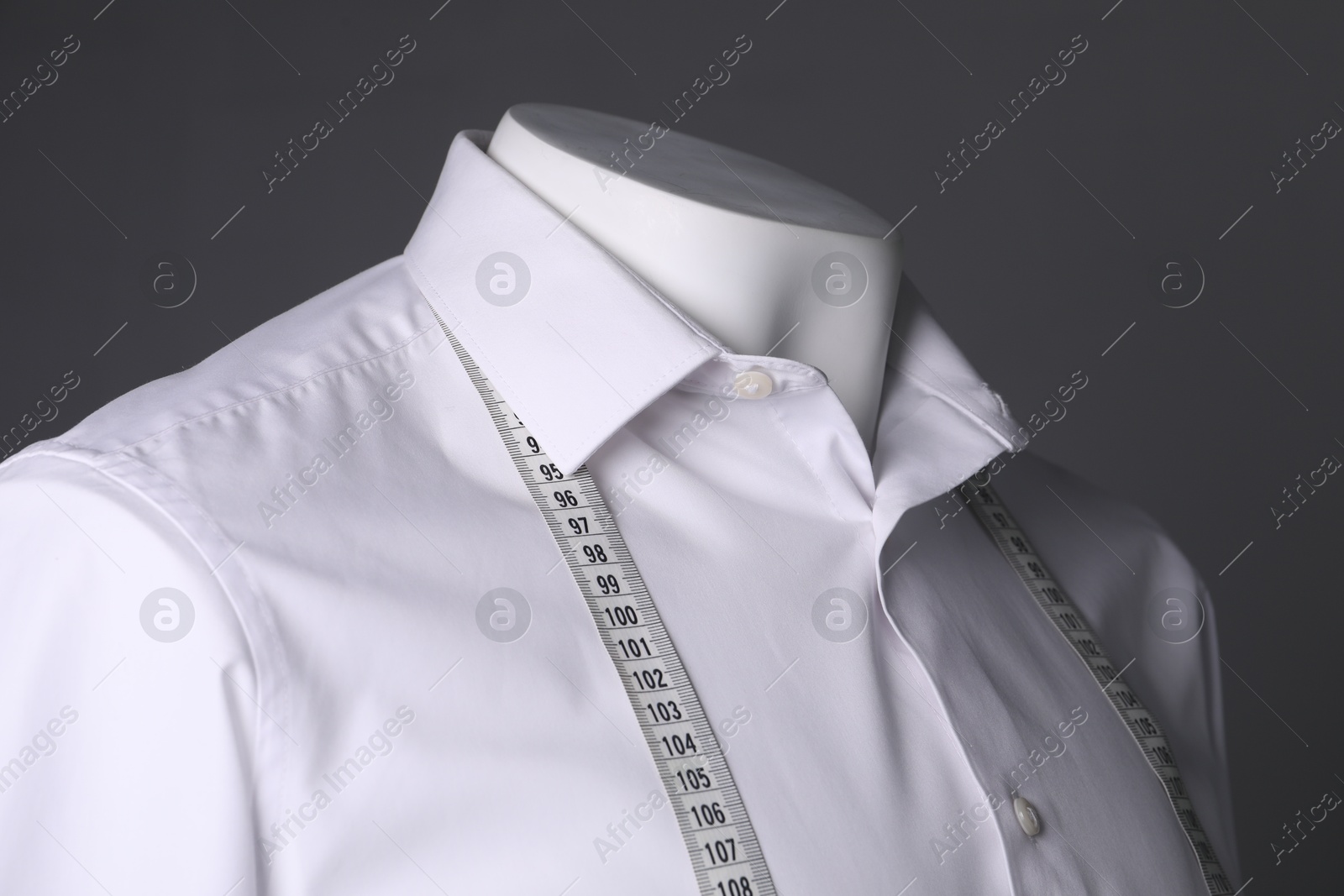 Photo of Male mannequin with white shirt and measuring tape on grey background, closeup