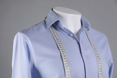 Photo of Male mannequin with light blue shirt and measuring tape on grey background, closeup