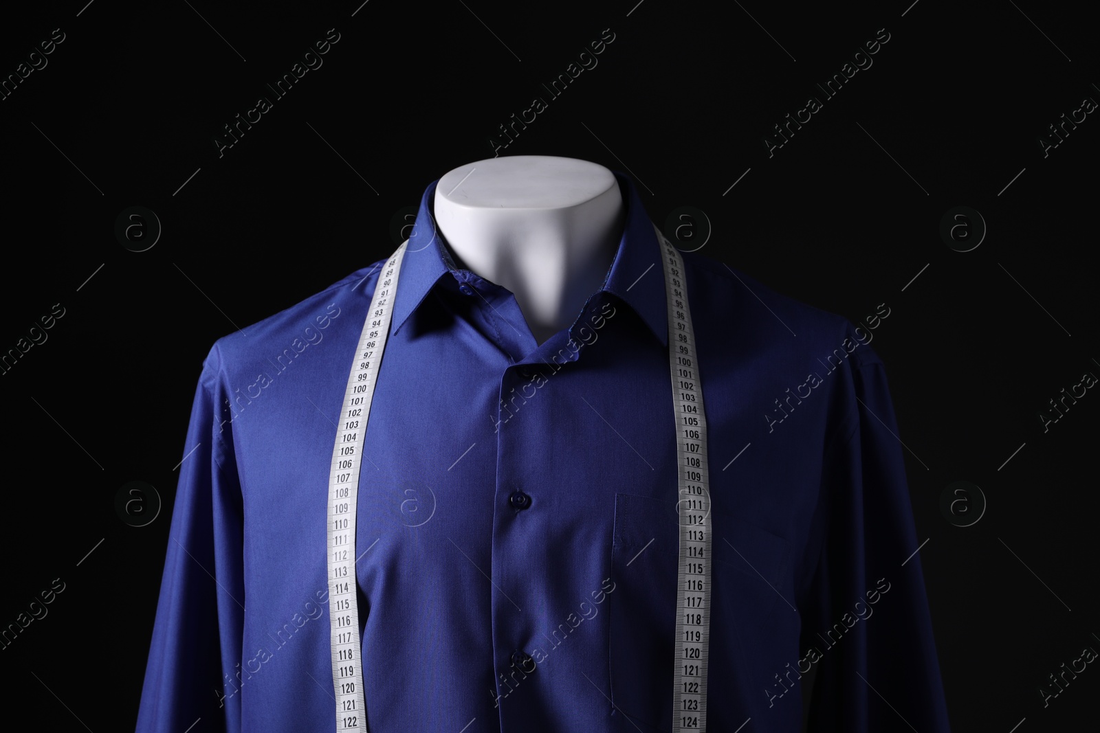 Photo of Male mannequin with blue shirt and measuring tape on black background, closeup