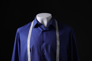 Photo of Male mannequin with blue shirt and measuring tape on black background, closeup