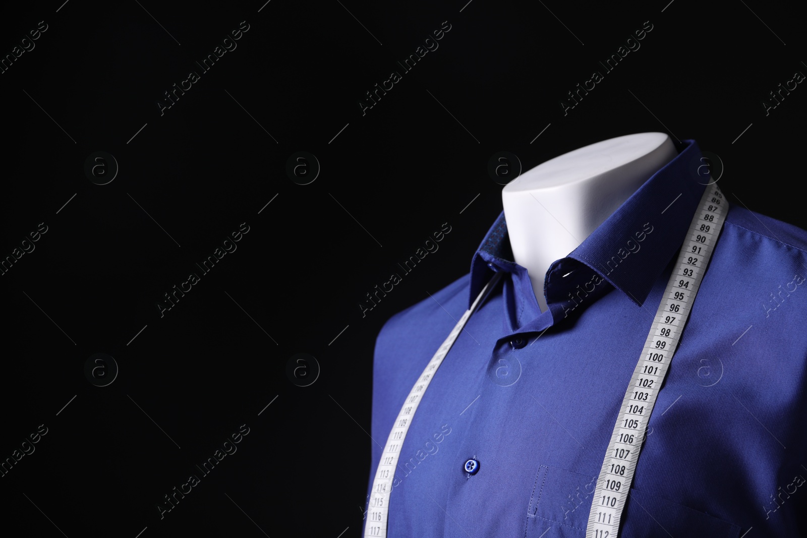 Photo of Male mannequin with blue shirt and measuring tape on black background, closeup. Space for text