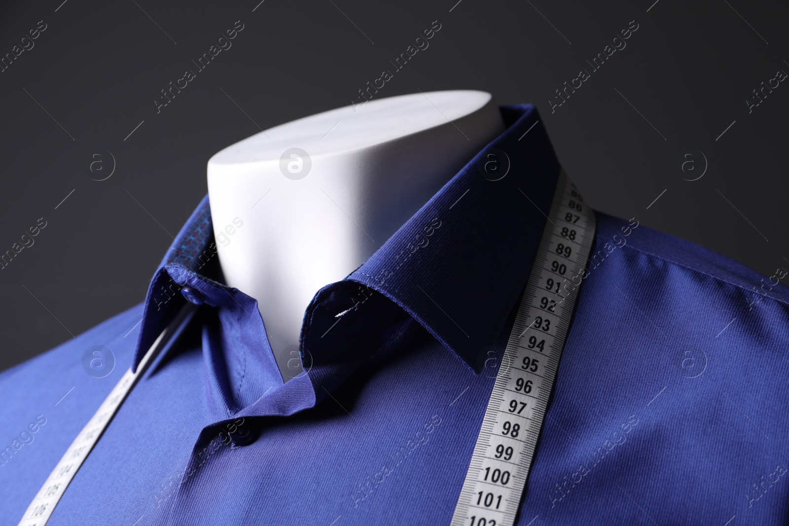 Photo of Male mannequin with blue shirt and measuring tape on black background, closeup