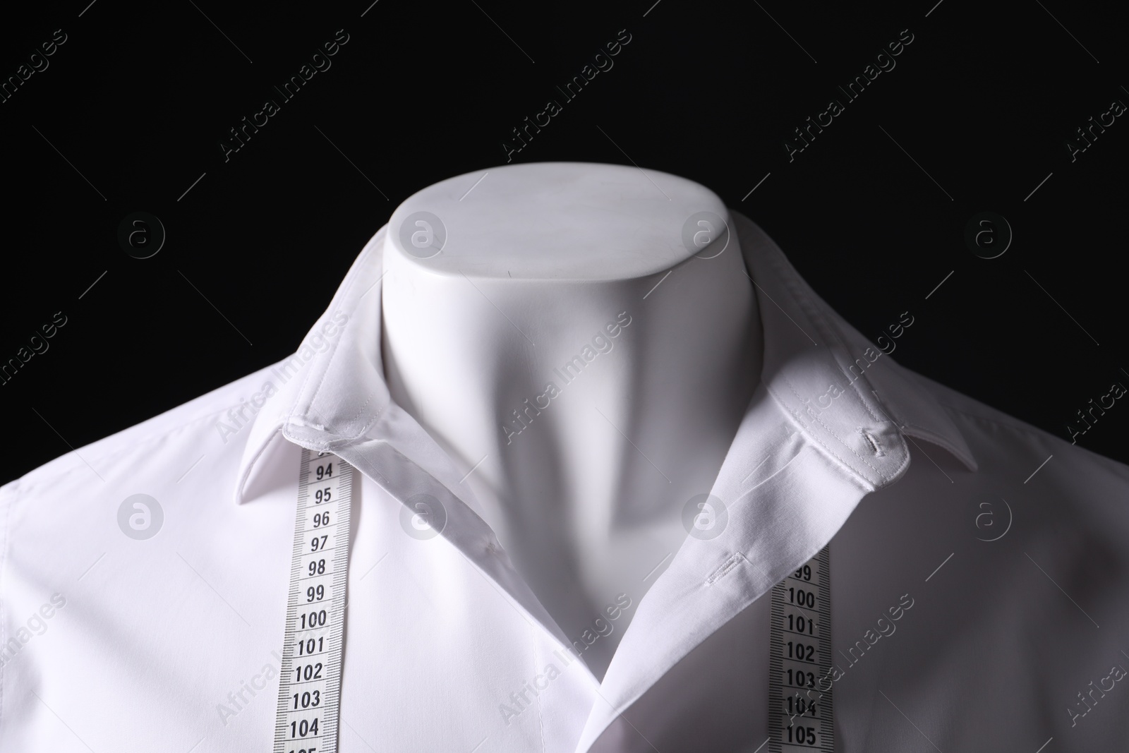 Photo of Male mannequin with white shirt and measuring tape on black background, closeup