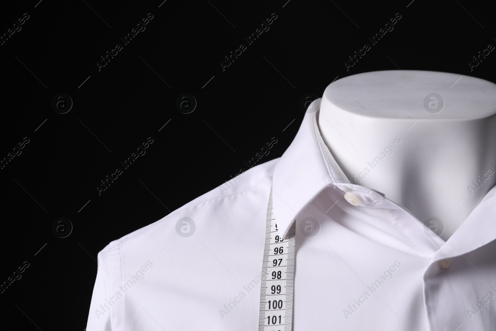 Photo of Male mannequin with white shirt and measuring tape on black background, closeup