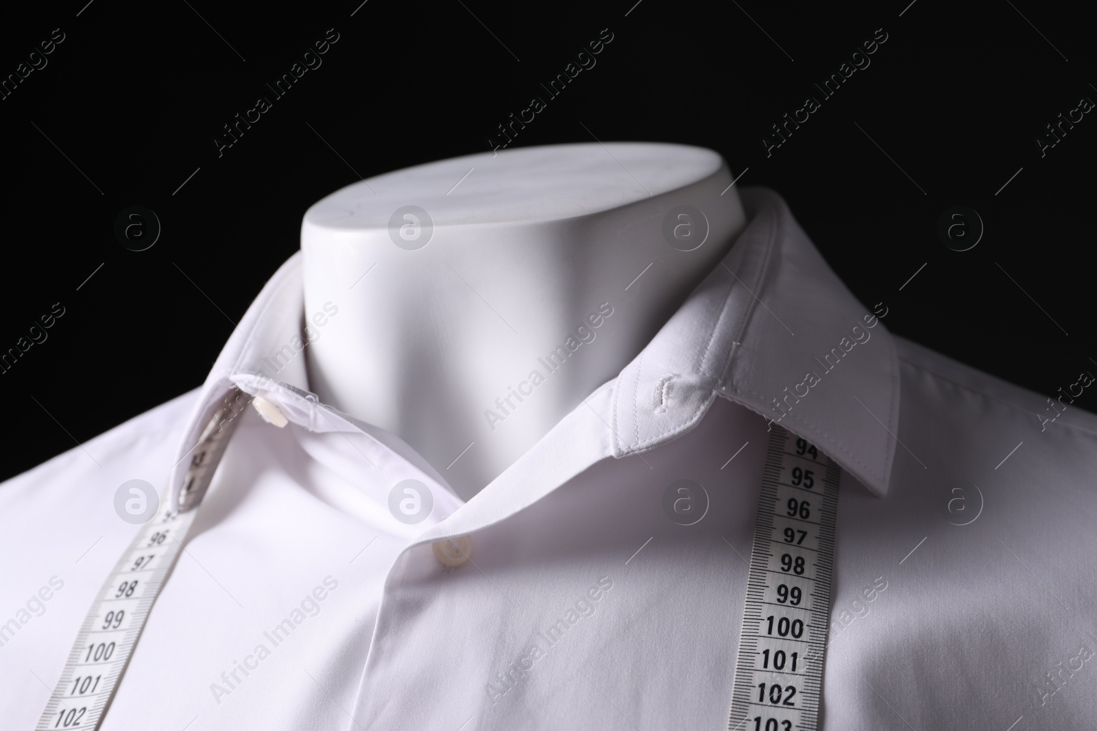 Photo of Male mannequin with white shirt and measuring tape on black background, closeup