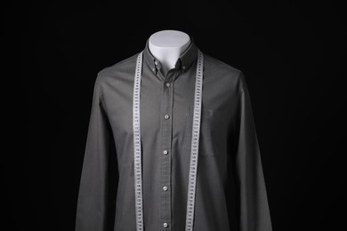 Male mannequin with grey shirt and measuring tape on black background