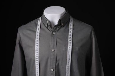 Male mannequin with grey shirt and measuring tape on black background