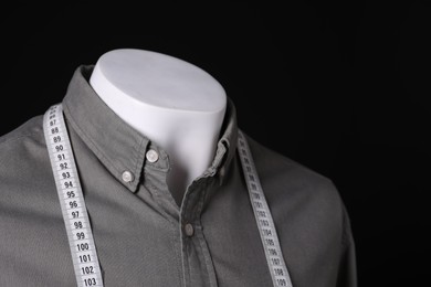 Photo of Male mannequin with grey shirt and measuring tape on black background, closeup