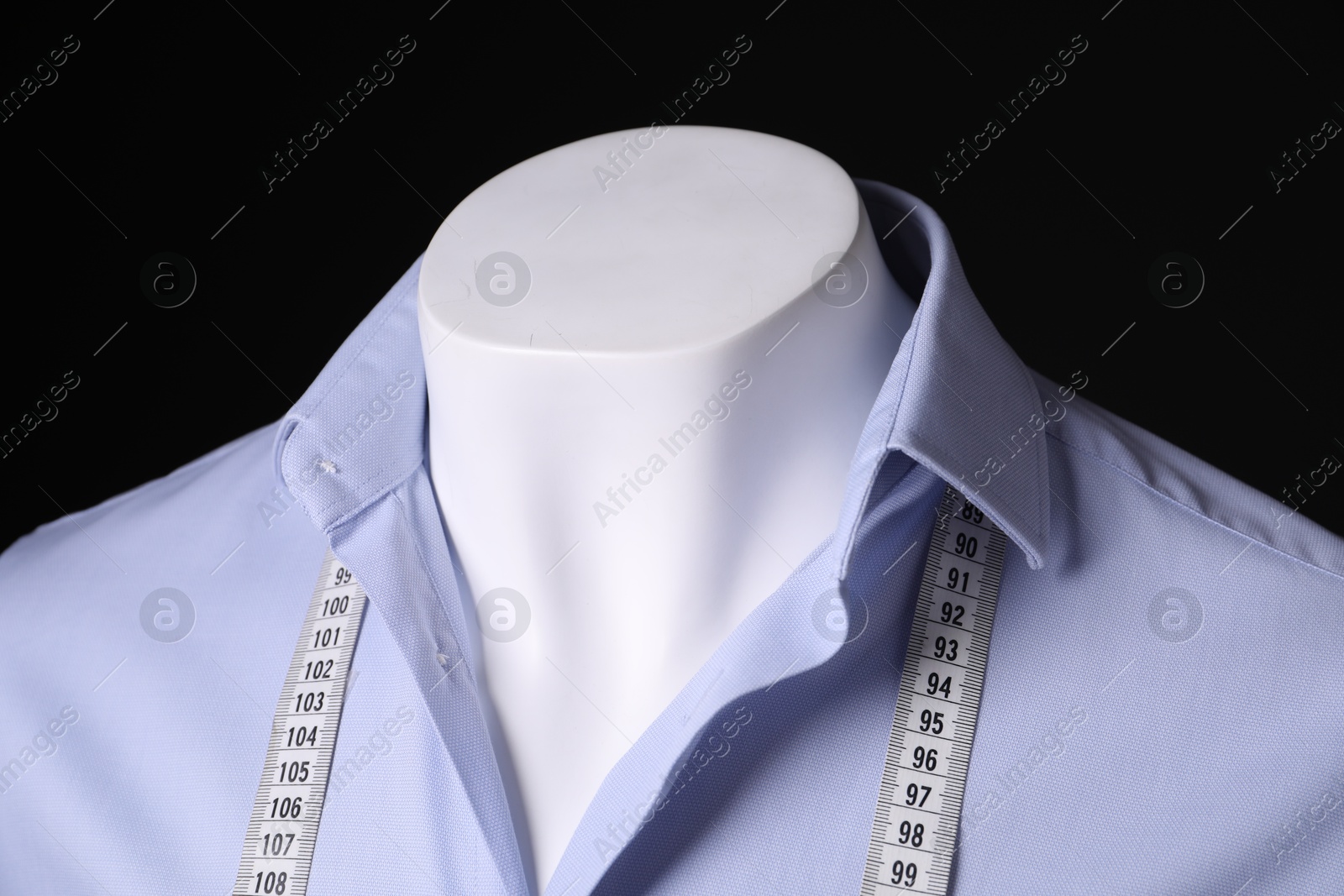 Photo of Male mannequin with light blue shirt and measuring tape on black background, closeup