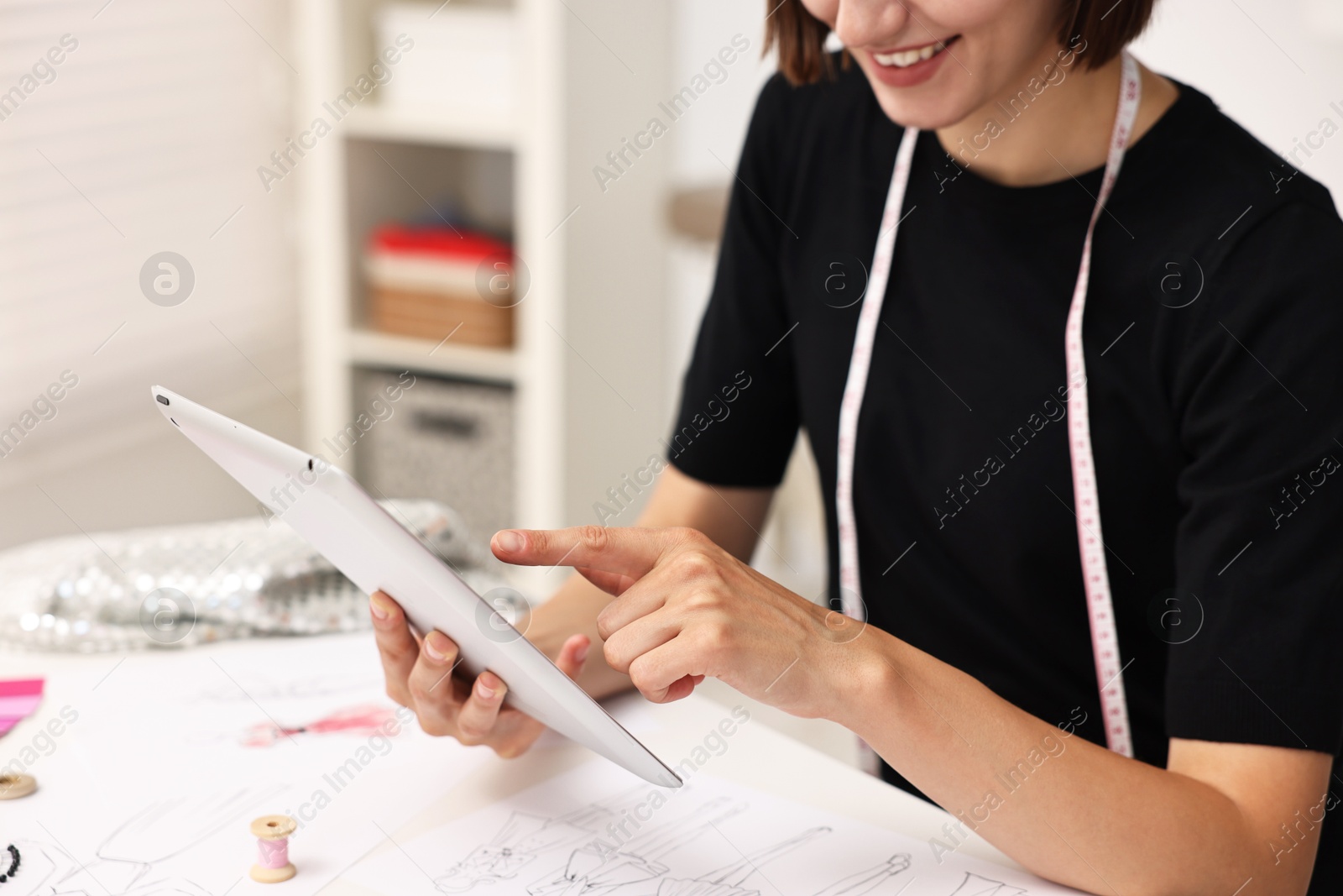 Photo of Fashion designer with tablet working in workshop, closeup