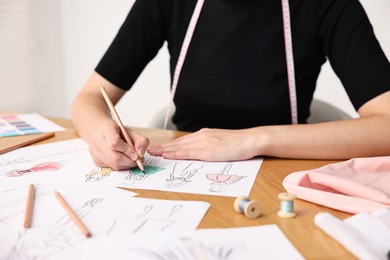 Fashion designer drawing sketch of beautiful dress at wooden table, closeup