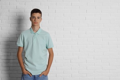 Photo of Teenage boy wearing light green t-shirt near white brick wall, space for text