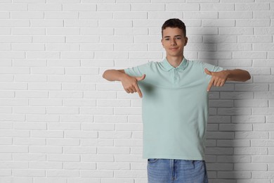 Photo of Teenage boy wearing light green t-shirt near white brick wall, space for text